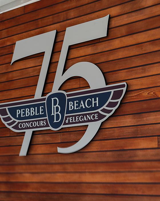 Seventy fifth anniversary Pebble Beach Concours badge on a wood wall