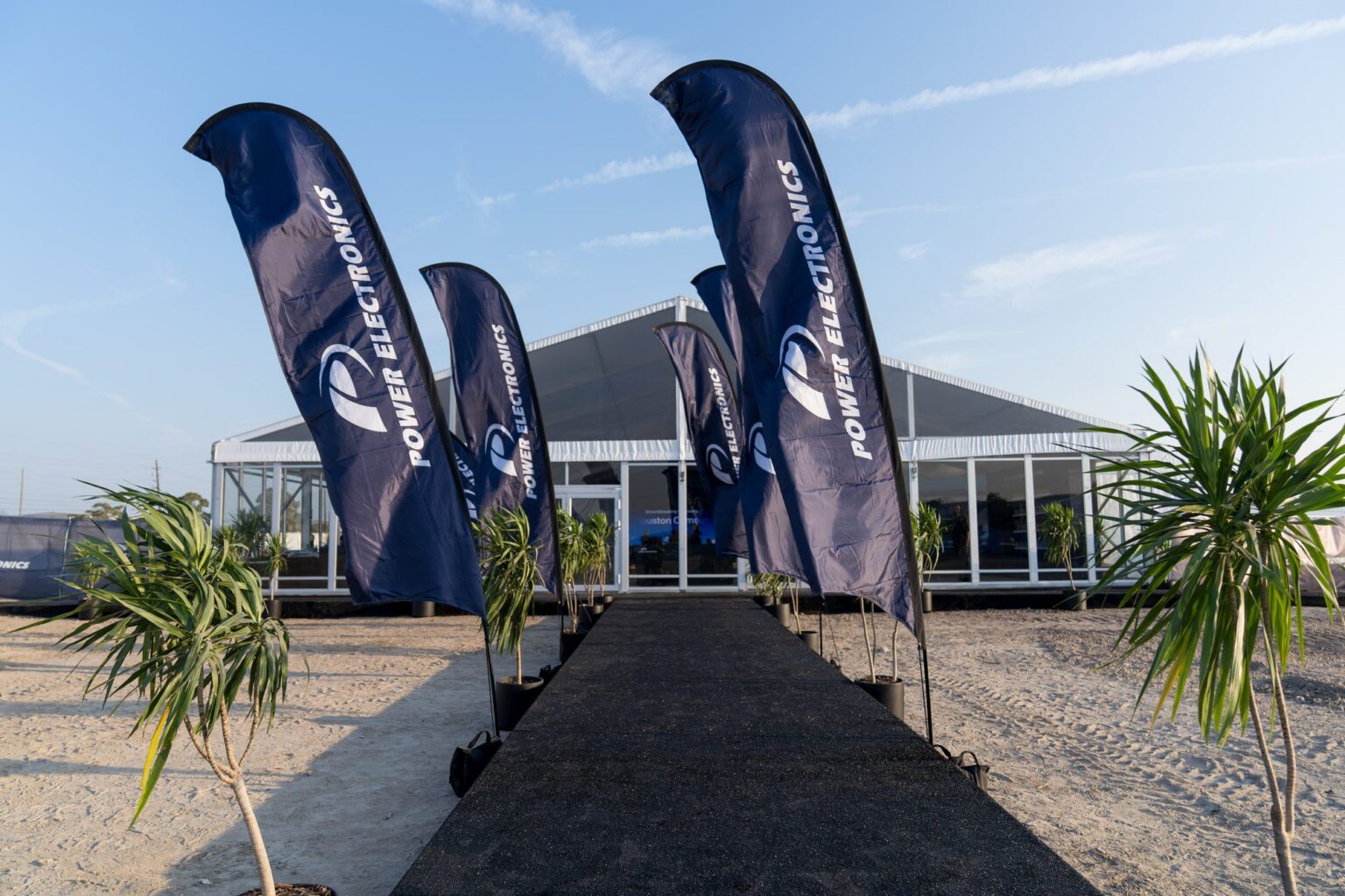 Power Electronics flags leading to the ceremony marquee on the cleared Houston Campus site