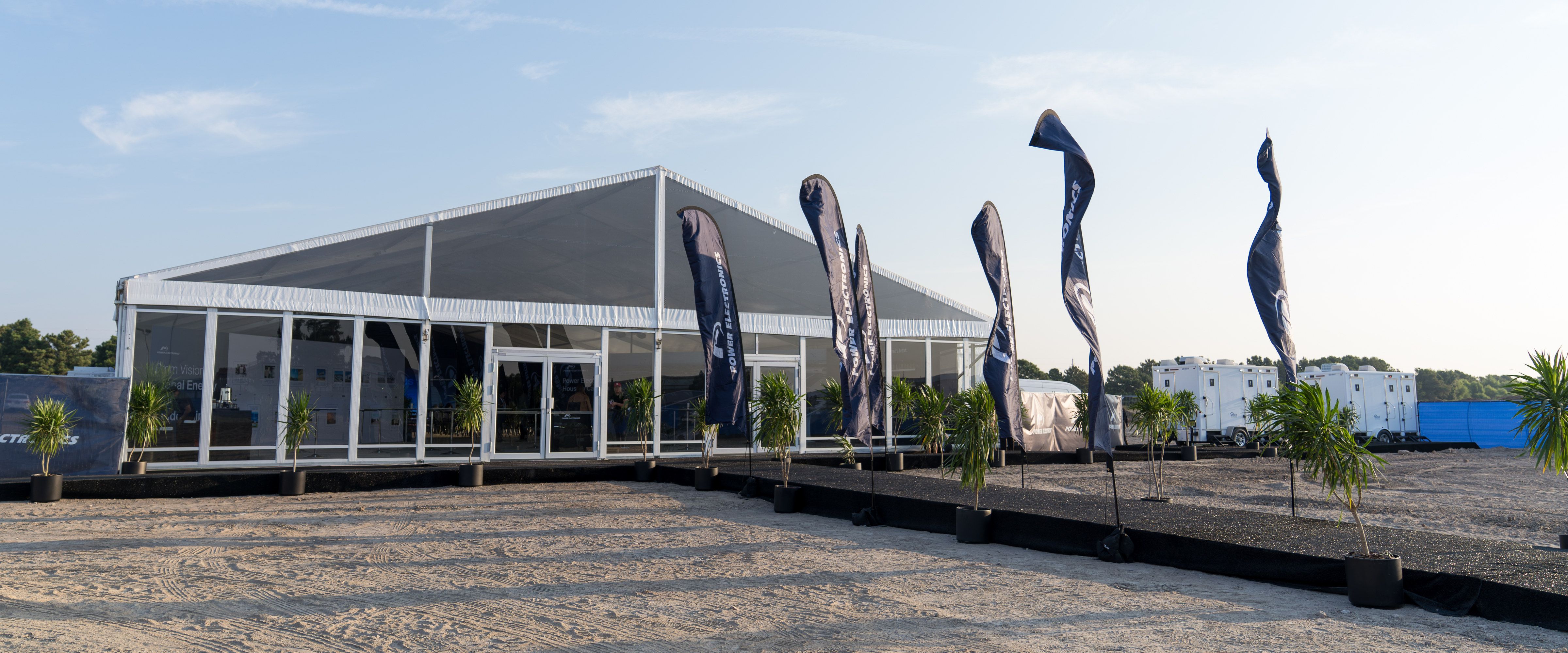Power Electronics flags and the ceremony marquee on the cleared Houston Campus site